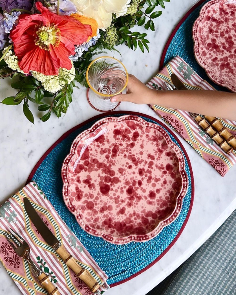 tablescape with blue placemats, red speckled plates, and bamboo silverware