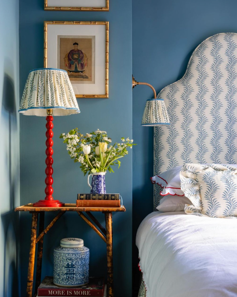 bedroom with blue walls, blue patterned headboard, red lamp